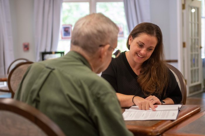 Andrea Dunseth going over paperwork with an older man at a table.