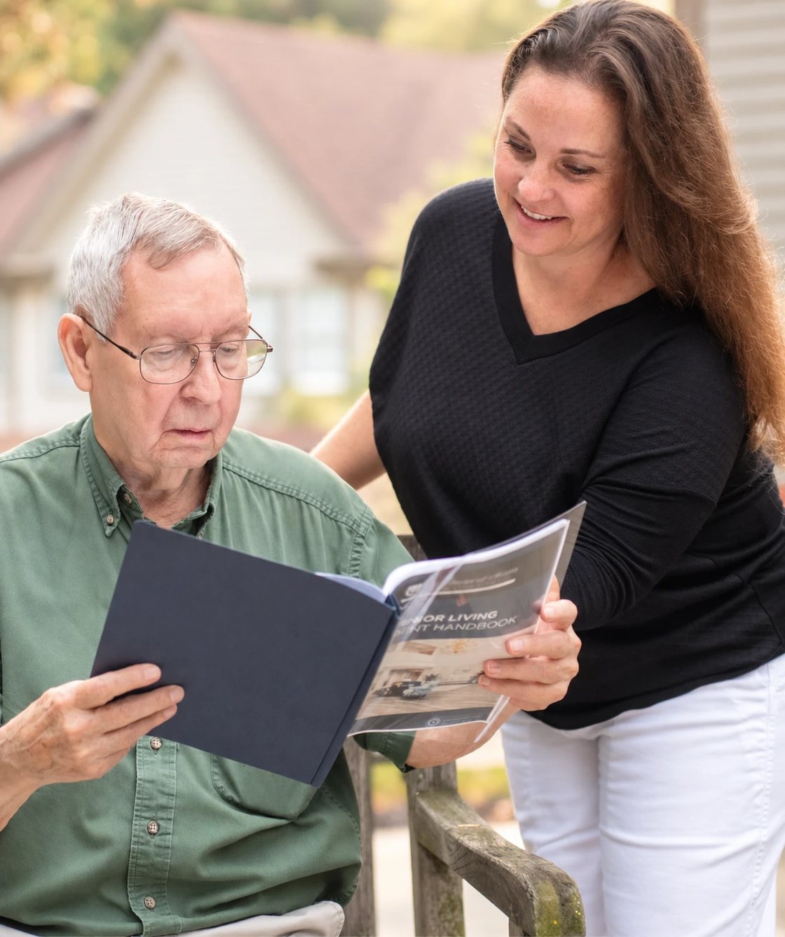 Andrea Dunseth reviewing a senior living resident handbook with an older man.